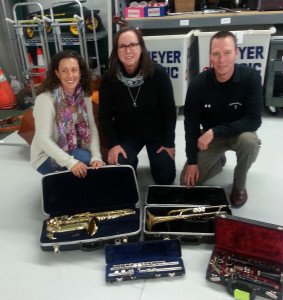 Carolyn Adams and Kristi Jurgensen picking up retired instruments from Mike Meyer.